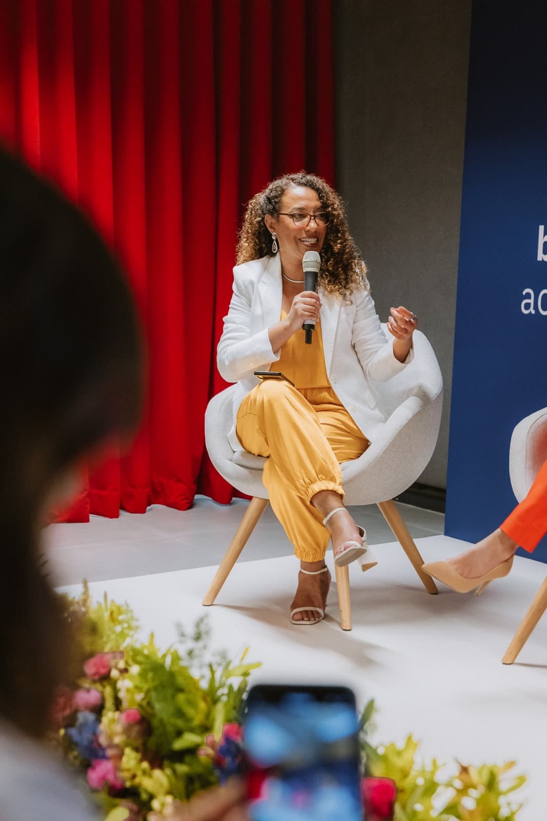 Elisangela Souza, sentada num painel, a falar ao microfone.
